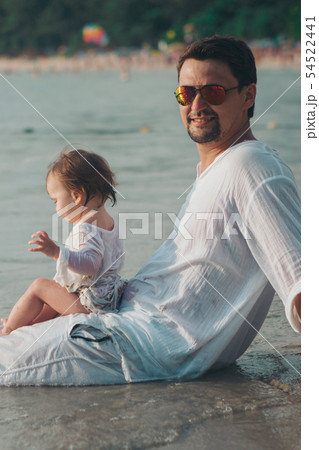 Dad in sunglasses holds baby on beach background Dad in sunglasses holds baby on beach background 54522441