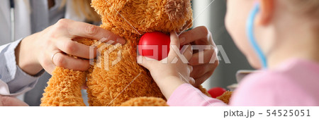 Little girl hold in arms toy red hear playing with teddy bear 54525051