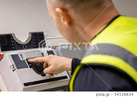 Electrician Checking Smoke Detector In Server Room Electrician Checking Smoke Detector In Server Room 54526634