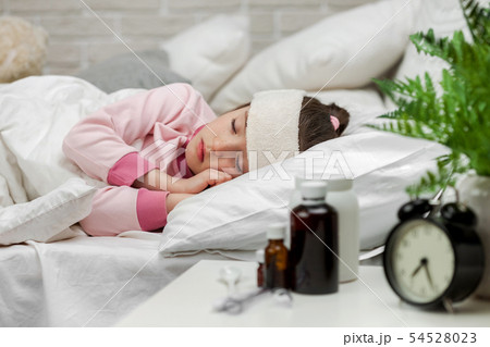 Sick little child girl lying in bed with thermometer. 54528023