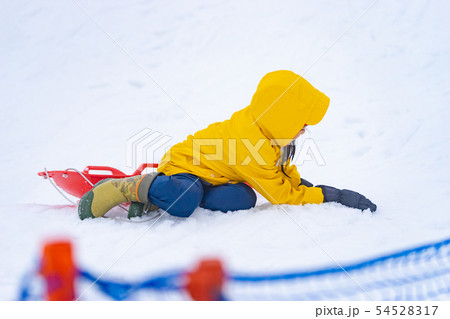 Little Japanese girl is sliding down the snow sled 54528317