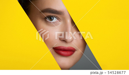 Woman With Red Lips Peering Into Hole In Yellow Paper 54528677