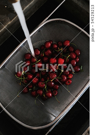 Fresh garden cherries being washed in strainer 54529213