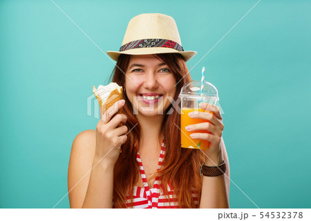 Woman wearing swimsuit and hat with fruit juice from a cup and icegream in her hands Woman wearing swimsuit and hat with fruit juice from a cup and icegream in her hands 54532378