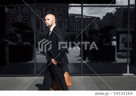 businessman with a bag near the office talking on the phone businessman with a bag near the office talking on the phone 54535164