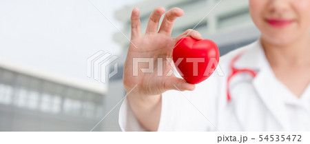 Doctor holding a red heart at hospital office. Doctor holding a red heart at hospital office. 54535472