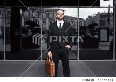 businessman with a bag near the office talking on the phone 54536334