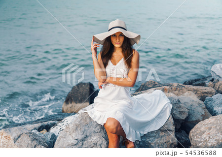 Pretty woman wearing white dress and pamela hat standing 54536588