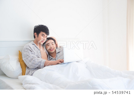 Young Gay couple wearing pajamas lying on bed 54539741