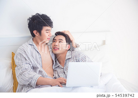 Young Gay couple wearing pajamas lying on bed 54539742