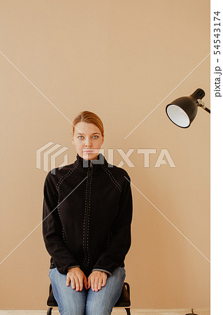 Short-haired woman in chair in front of studio light Short-haired woman in chair in front of studio light 54543174