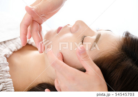 フェイスマッサージを受ける女性と施術者の手元 54545703