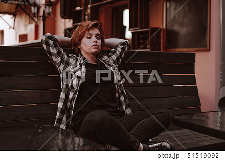 Young woman with short red hair in a bar put her legs on the bench Young woman with short red hair in a bar put her legs on the bench 54549092
