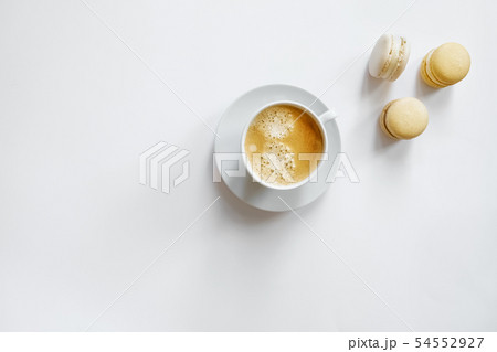White cup of coffee with yellow macarons. White cup of coffee with yellow macarons. 54552927