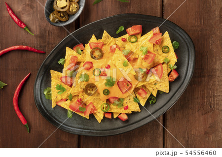 Nachos, Mexican tortilla chips, shot from above with a cheese sauce, chili and jalapeno peppers 54556460