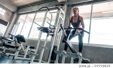 Woman is lifting weight on squat workout machine Woman is lifting weight on squat workout machine 54559820
