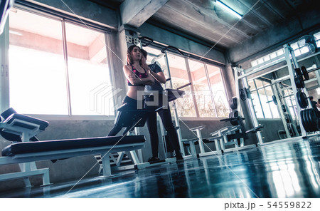 Female is working out on Ab machine with trainer Female is working out on Ab machine with trainer 54559822