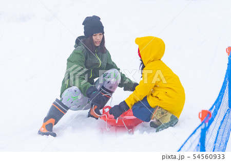 Mother is helping her daughter to ride the sled 54560933
