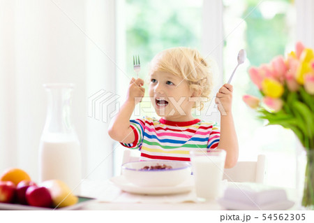 Child eating breakfast. Kid with milk and cereal. Child eating breakfast. Kid with milk and cereal. 54562305