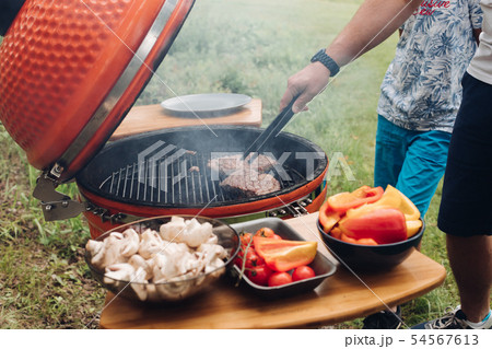 Unrecognizable man cooking meat on grill.Table 54567613