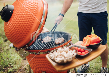 Unrecognizable man cooking meat on grill.Table 54568331