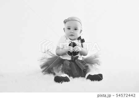 a little girl in a dress sits on the floor 54572442