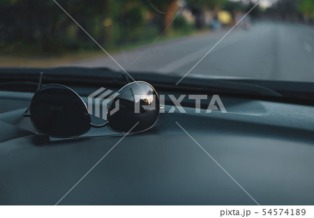 Sunglasses on car panel with view of road Sunglasses on car panel with view of road 54574189