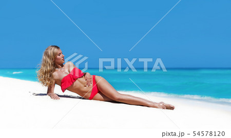 Slim tanning woman with long blond hair lying on 54578120