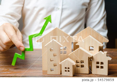 A man holds a green arrow up near a set of houses 54579859