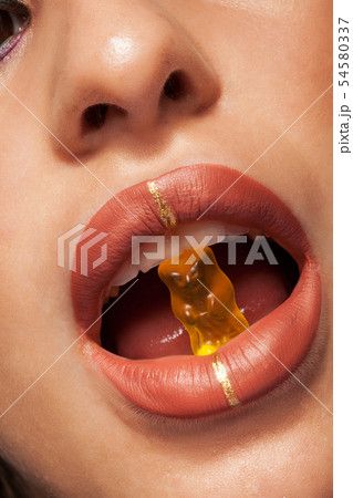 Close up view of beautiful woman lips with gummy bear 54580337