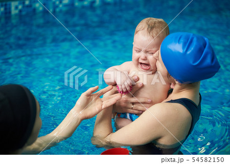 Little baby boy in diaper crying, afraid of water and swimming. Mother calming baby, holding on hand 54582150