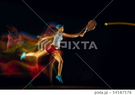 One caucasian woman playing tennis on black background in mixed light 54587576