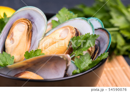 Boiled mussels with parsley and lemon in black dish 54590076