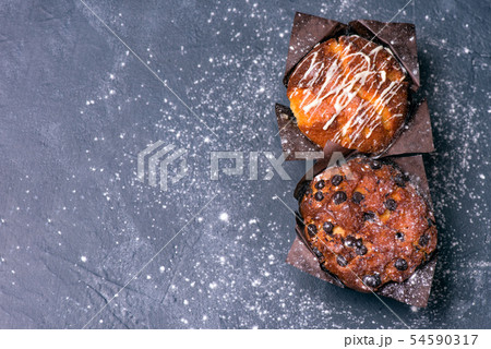 Close up. Dark key. Muffins with chocolate pieces in black paper Close up. Dark key. Muffins with chocolate pieces in black paper 54590317