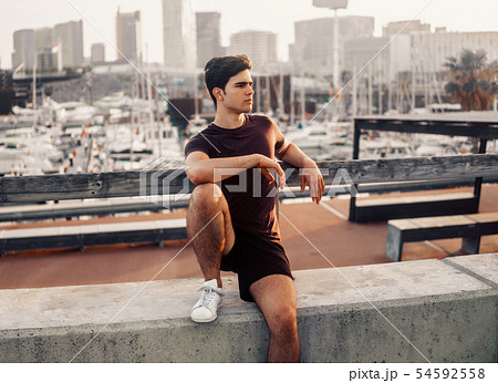 Young athletic man after running at park with skyscrapers background 54592558