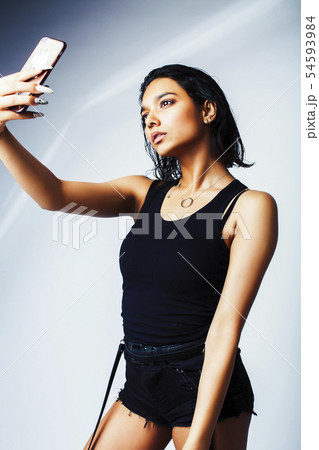 young pretty indian girl posing with phone isolated on white background, lifestyle modern fashion 54593984