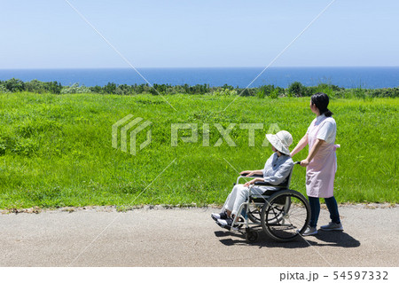車いすで散歩するシニアと介護ヘルパー 車いすで散歩するシニアと介護ヘルパー 54597332