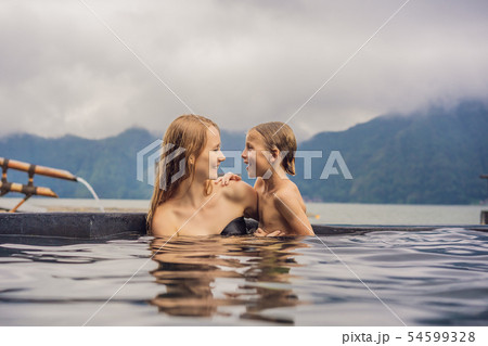 Mom and son travelers in Hot Springs in Bali on the background of lake. Traveling with children 54599328