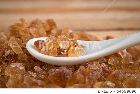 Natural rock sugar in white spoon on rustic table 54599690