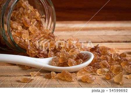 Natural rock sugar in white spoon on rustic table 54599692