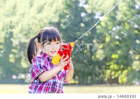 新緑の樹木を背景に水鉄砲で遊ぶ幼い女の子。自由、遊び、子供、幸せ、元気イメージ 新緑の樹木を背景に水鉄砲で遊ぶ幼い女の子。自由、遊び、子供、幸せ、元気イメージ 54600392