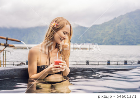 Geothermal spa. Woman relaxing in hot spring pool against the lake. hot springs concept. Drinking 54601371