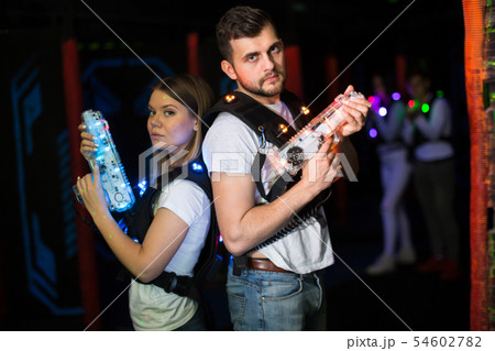 Couple standing back to back with laser guns Couple standing back to back with laser guns 54602782