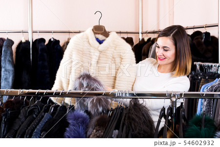 Female customer examining white mink jacket 54602932