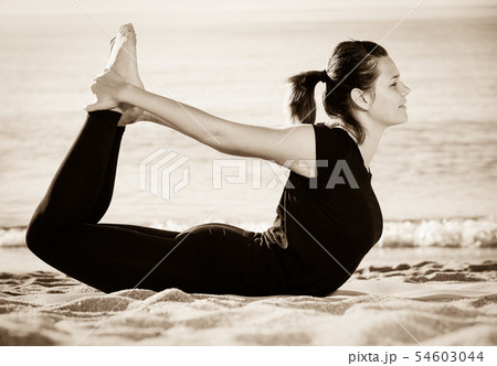 Sportswoman in black T-shirt is practicing set of stretching exercises 54603044