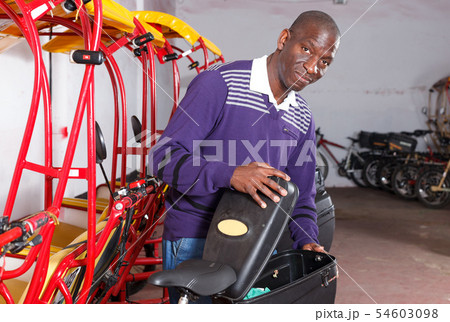 Driver of pedicab inspecting luggage basket 54603098
