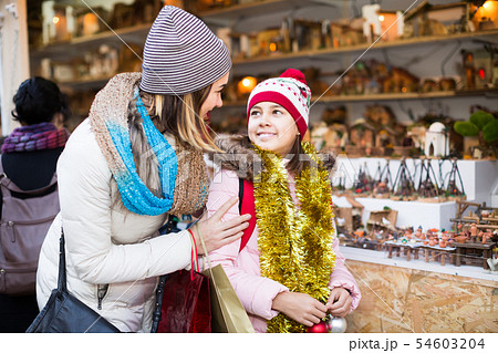 Little girl with cheerful mom buying figures and workpiece for creating Christmas scenes Little girl with cheerful mom buying figures and workpiece for creating Christmas scenes 54603204