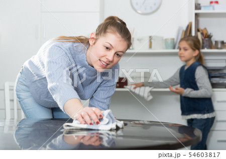 Mother and daughter dusting furniture 54603817