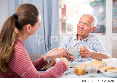 Mature father talks to adult daughter at the table. Tea party Mature father talks to adult daughter at the table. Tea party 54603820