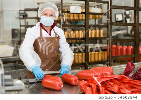 Woman hanging up sausages on rails 54603844